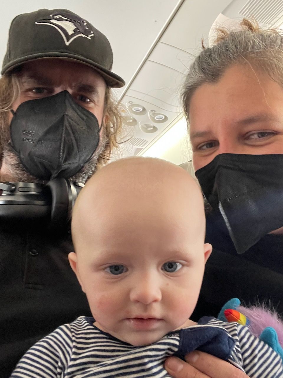 A selfie of a baby and a couple, on a plane.