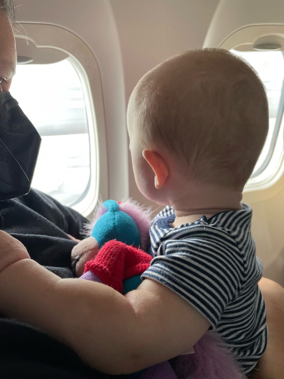 A baby looks out an airplane window