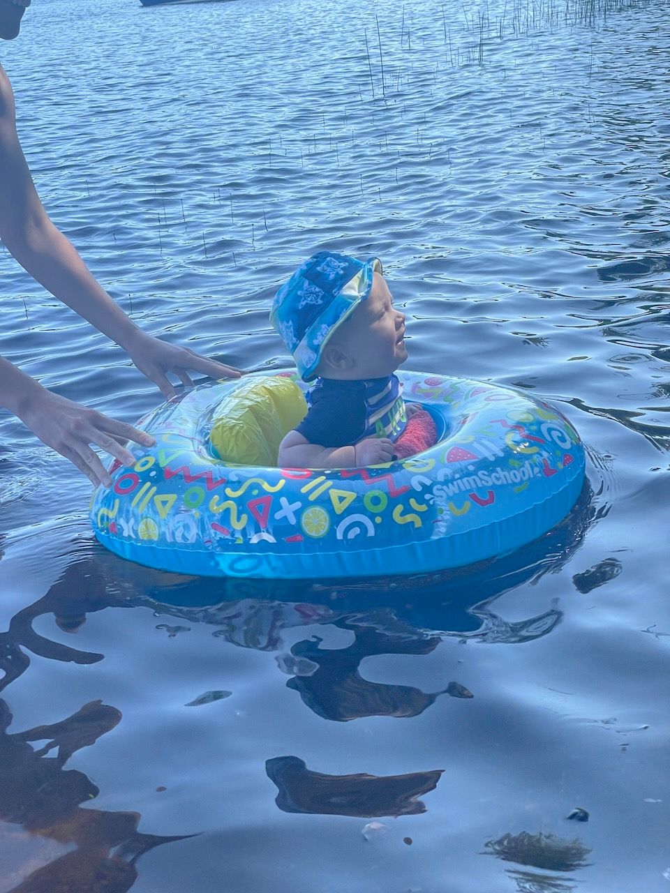 A baby in a lake, held up by a floatie