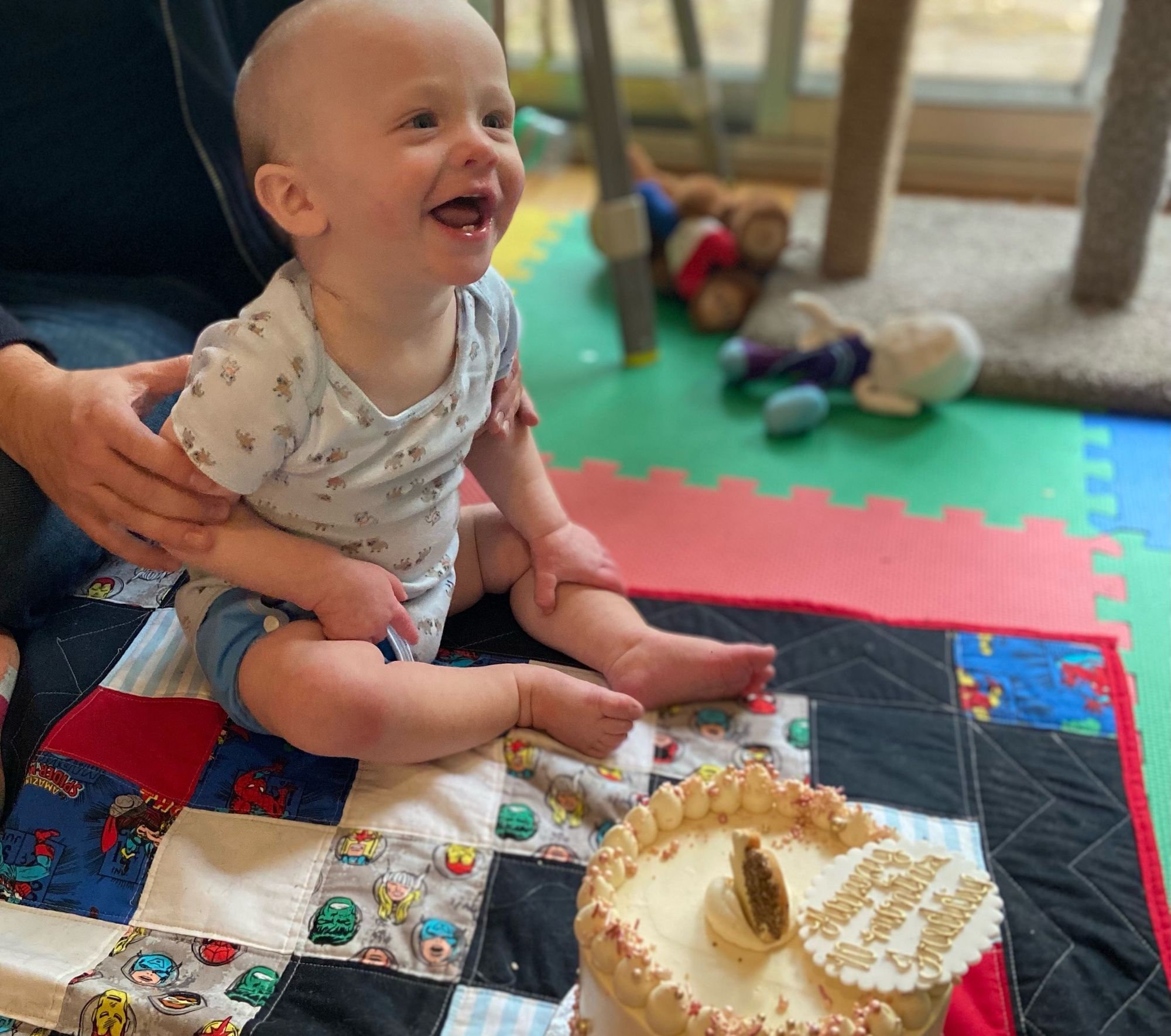 Freddie is seated, being held, in front of a cake.