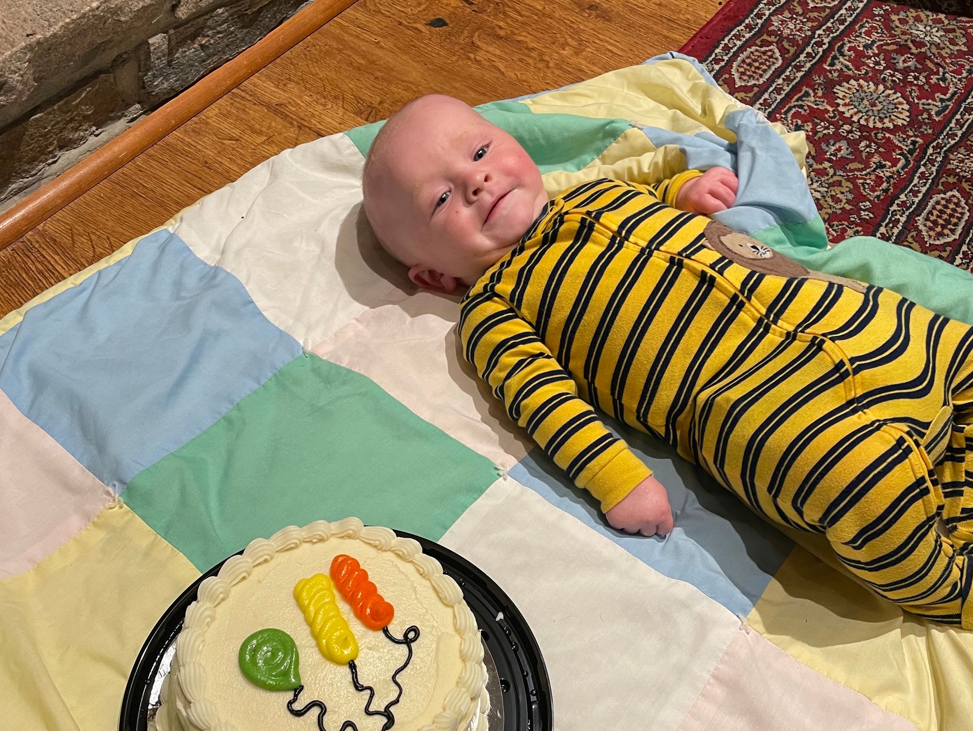 Freddie in a striped-yellow pajama outfit, is next to a cake.