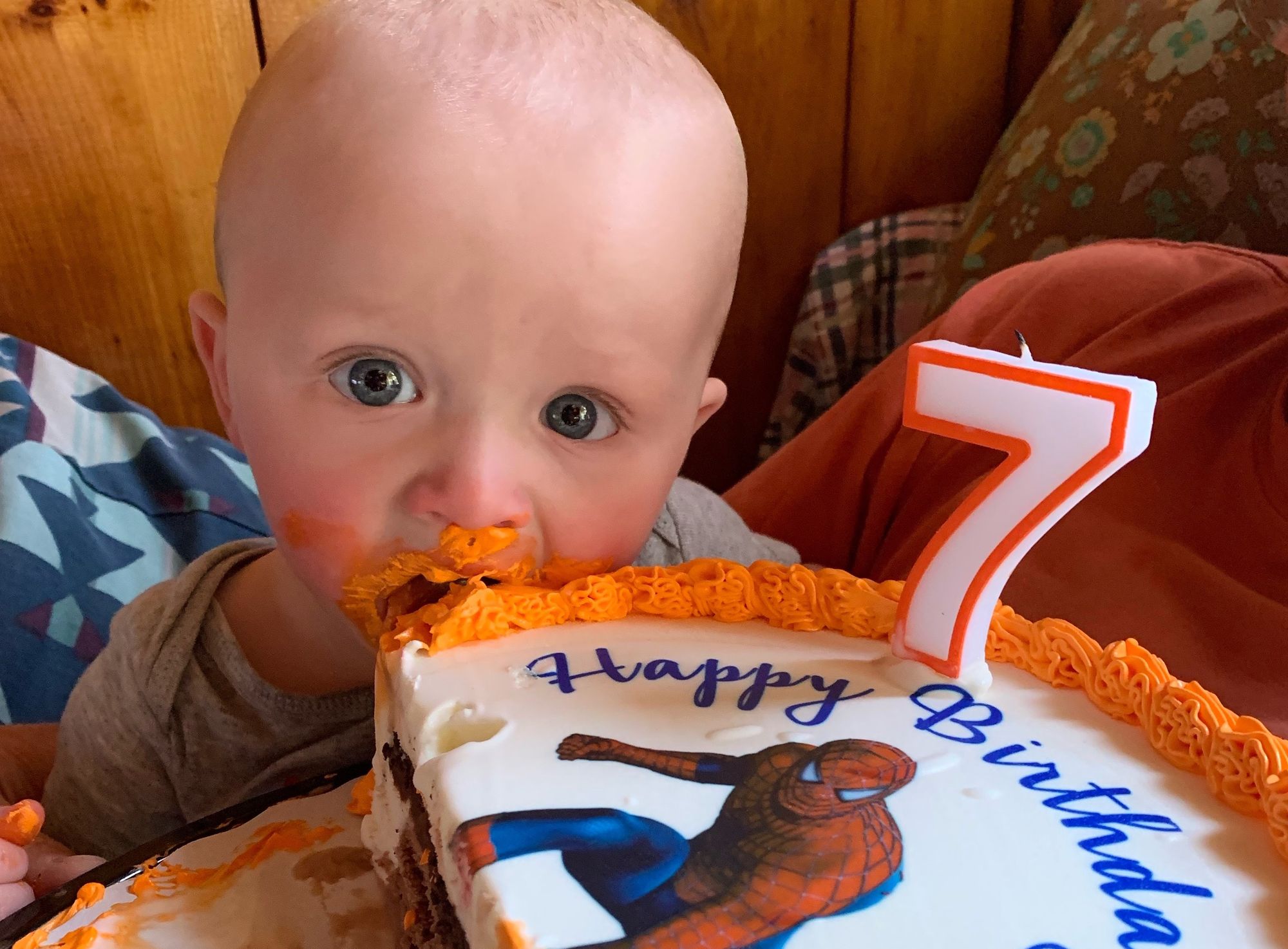 A close-up of Freddie with an orage-frosted cake with Spider-Man on the top.