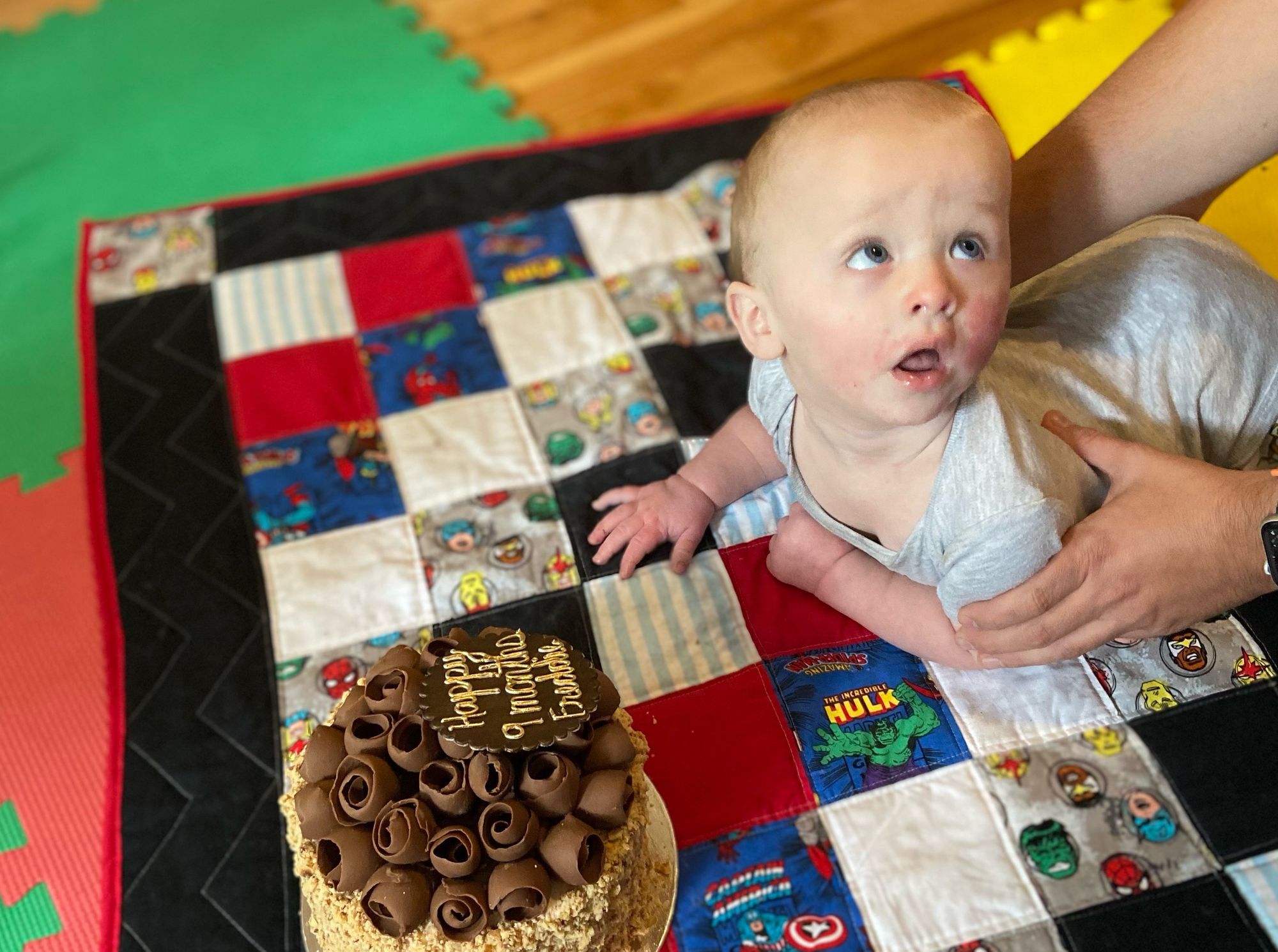 Freddie held on his stomach as he is posed in front of a cake.